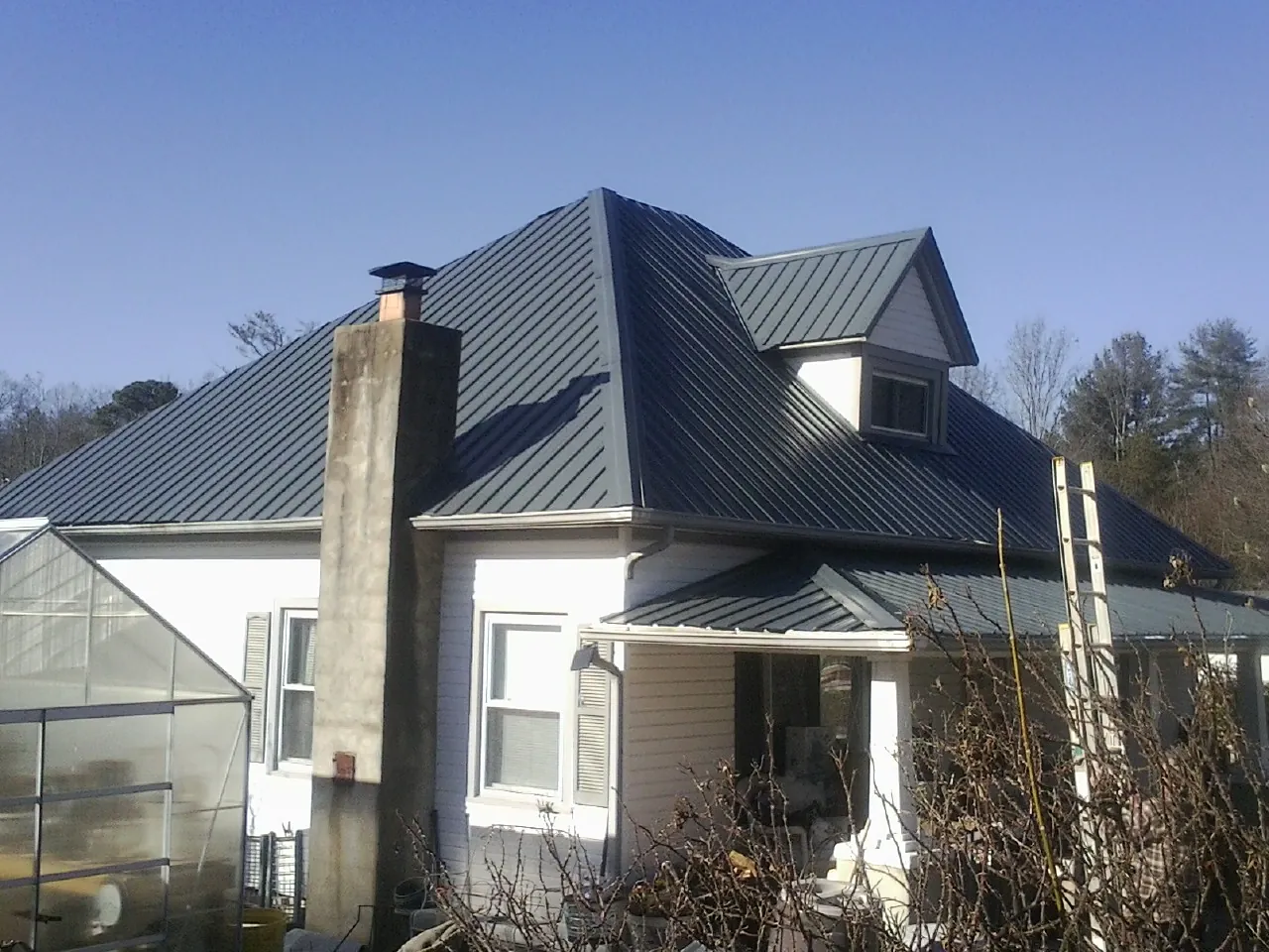 Dark blue standing seam metal roof on a white farmhouse with dormer — Slate & Tile Roof Repair by Roofing Brothers in Londonderry