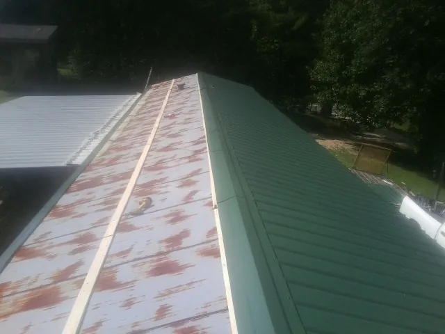 Old rusted panels beside newly installed green metal roofing — Wind Damage Roof Repair by Roofing Brothers in Londonderry