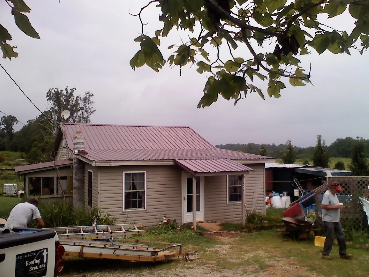 Crew finishing a mauve metal roof on a small farmhouse in Londonderry