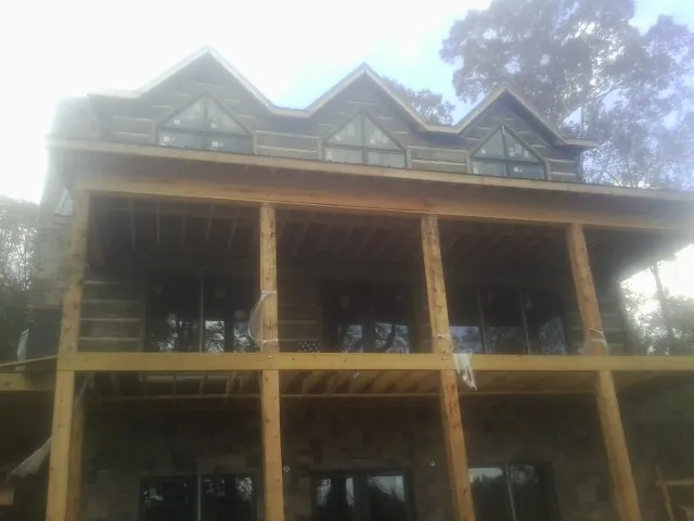 Dormers and porch framing on a large log home under construction — Roof Coating work by our crew in Londonderry